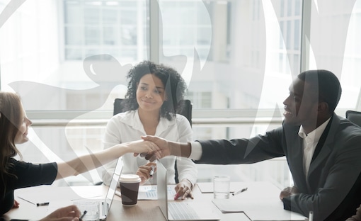 Business people shaking hands across a meeting table, symbolizing partnership or agreement