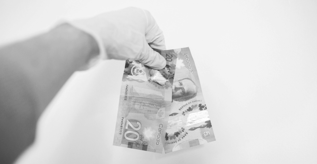 This image of Canadian currency in a gloved hand highlights our discussion topic: counterfeiting and replicas in Canada, what brands can learn about them, and how to fight back.