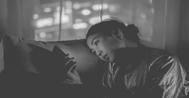 This image of a lady on a couch, browsing her phone, illustrates our discussion topic: social media monitoring, social media scams, and malicious ads that target brands.