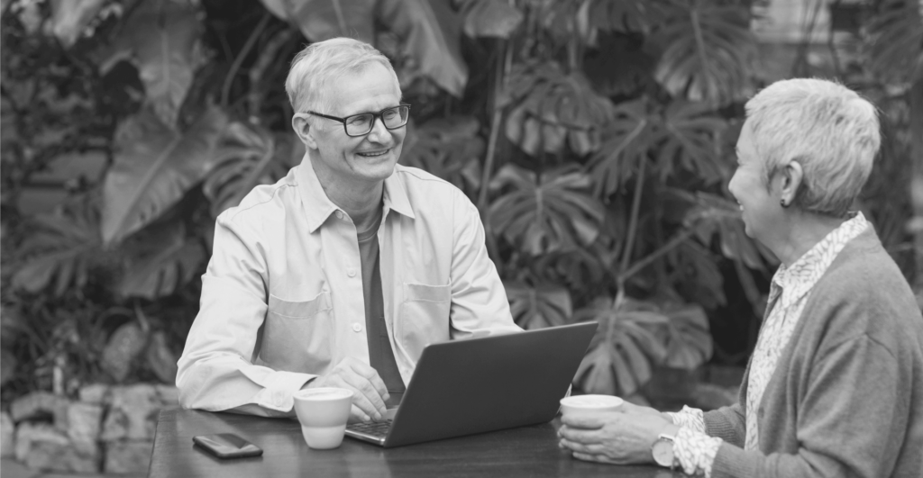 This image of two people smiling at a computer desk in the garden illustrates our discussion topic: domain names vs. trademarks