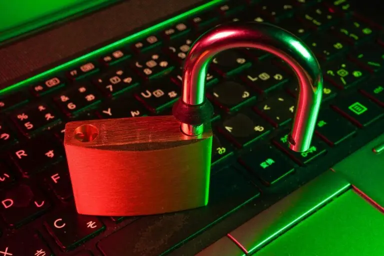 An open padlock rests on a laptop keyboard, illuminated in red and green light, symbolizing cybersecurity themes.