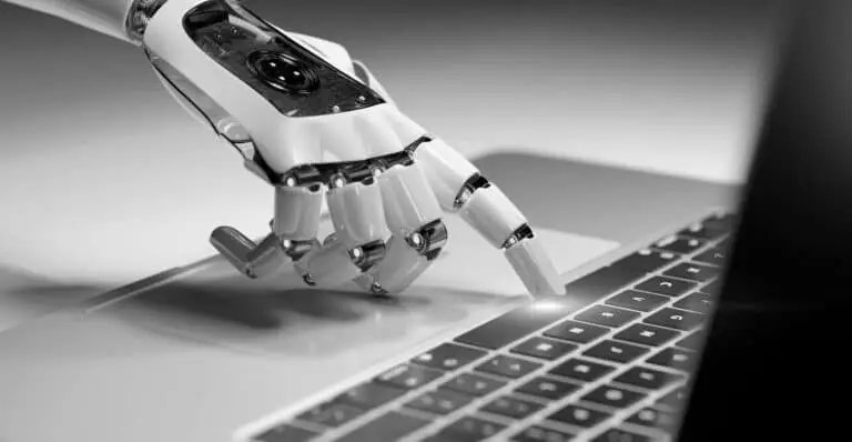 Robotic hand interacting with a laptop keyboard, symbolizing artificial intelligence and automation in digital technology